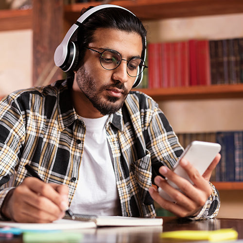 Man using a smartphone while learning in a library