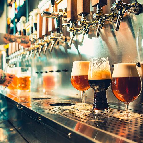 Different craft beers being poured at a brewery