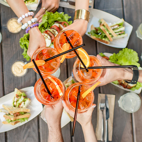 Friends clinking glasses with cocktail drinks outdoors