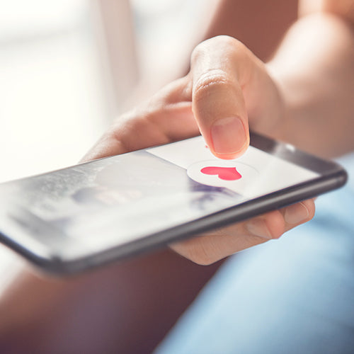 Finger tapping heart icon on screen in smartphone app
